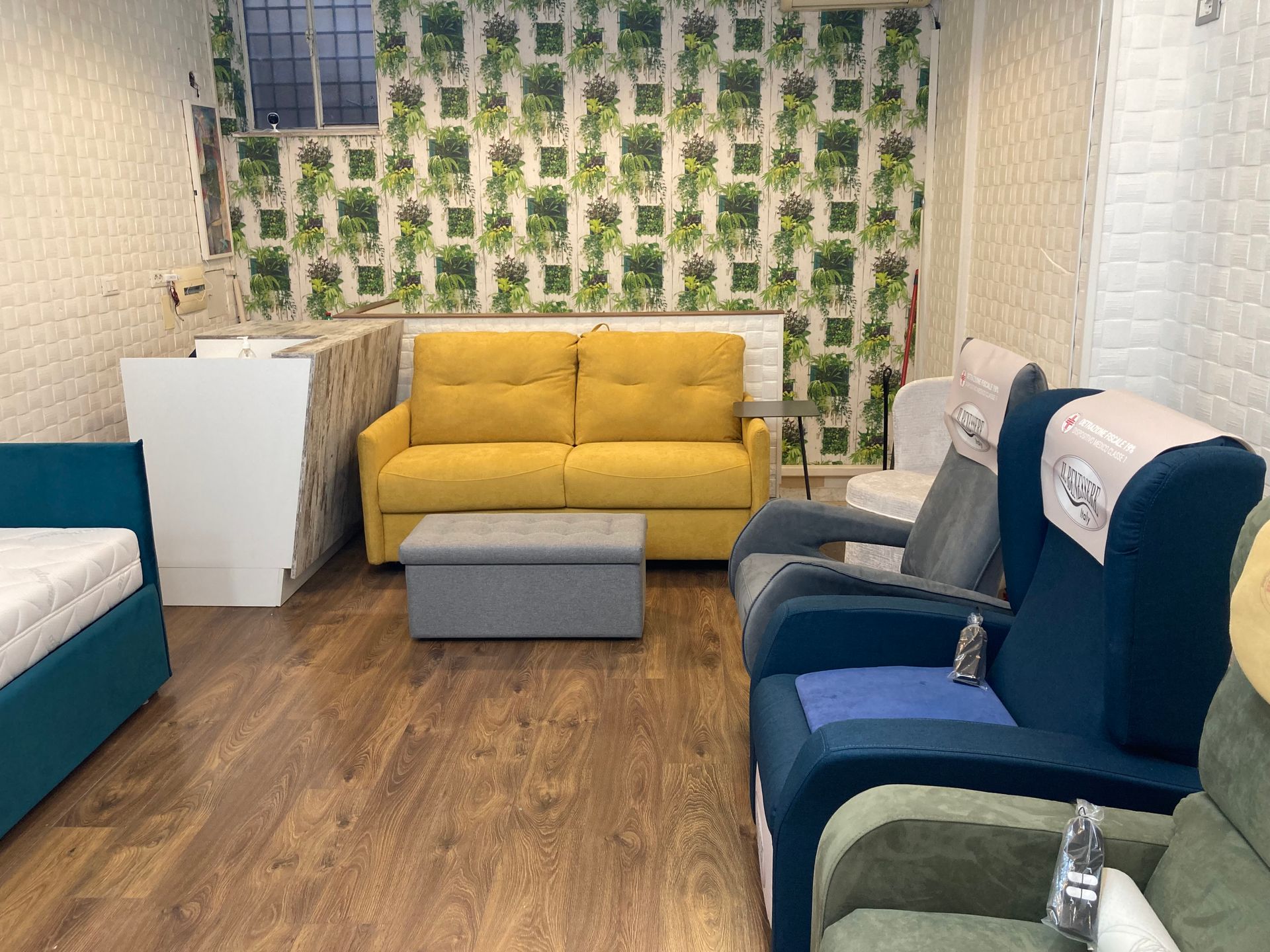 showroom con divano giallo e poltrone grigie e blu