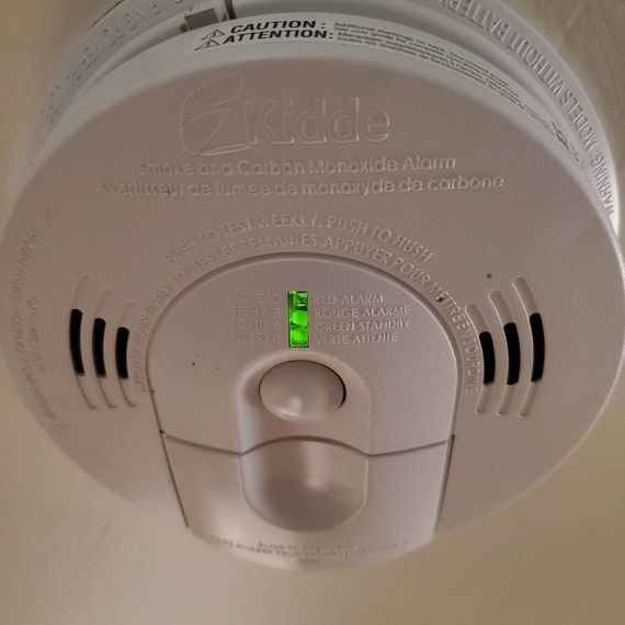 White ceiling smoke alarm with green status light and test button