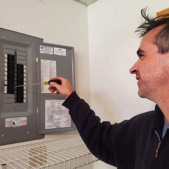 Man opening an electrical circuit breaker panel indoors