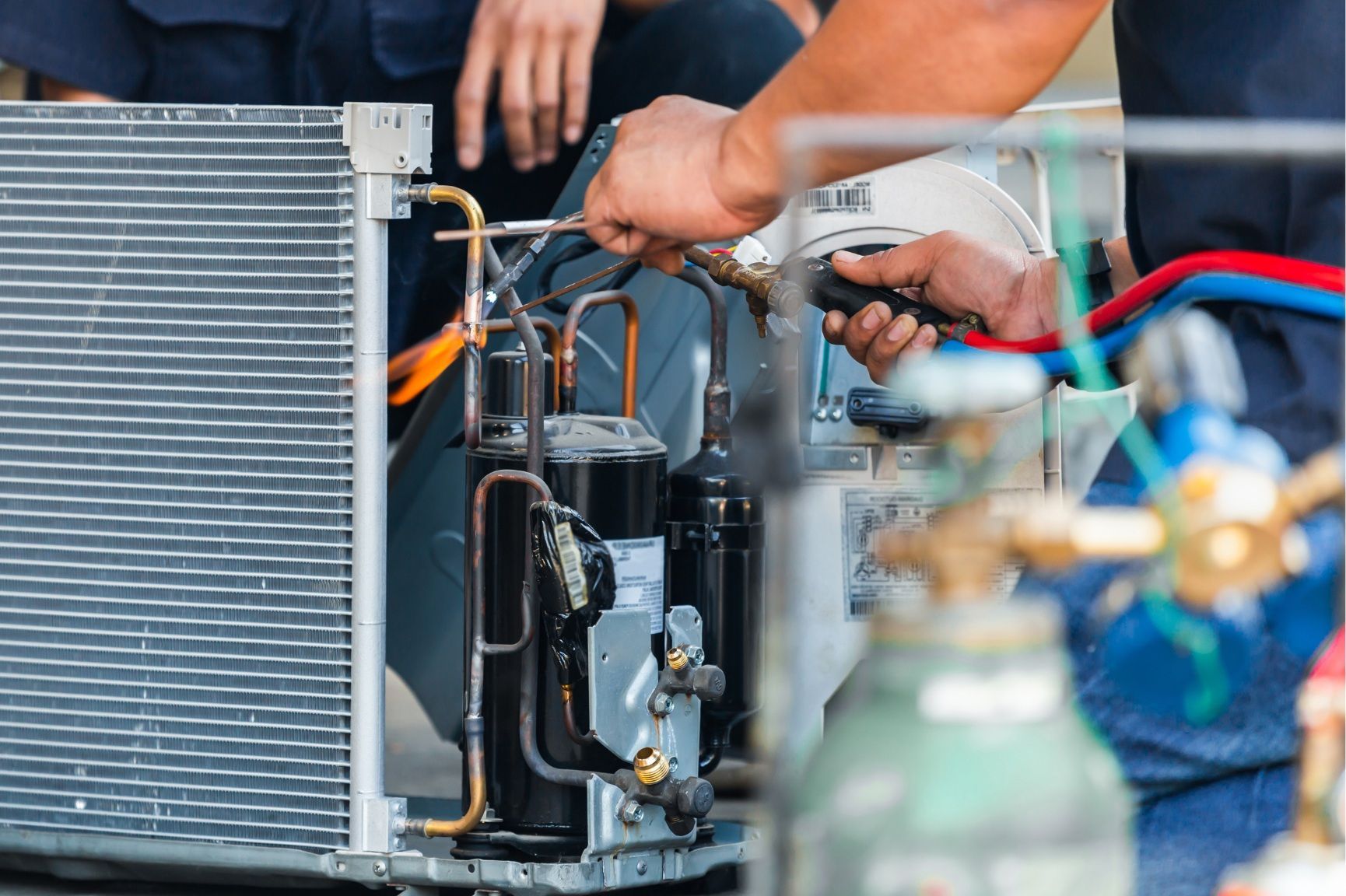 A man is working on an air conditioner with a wrench.