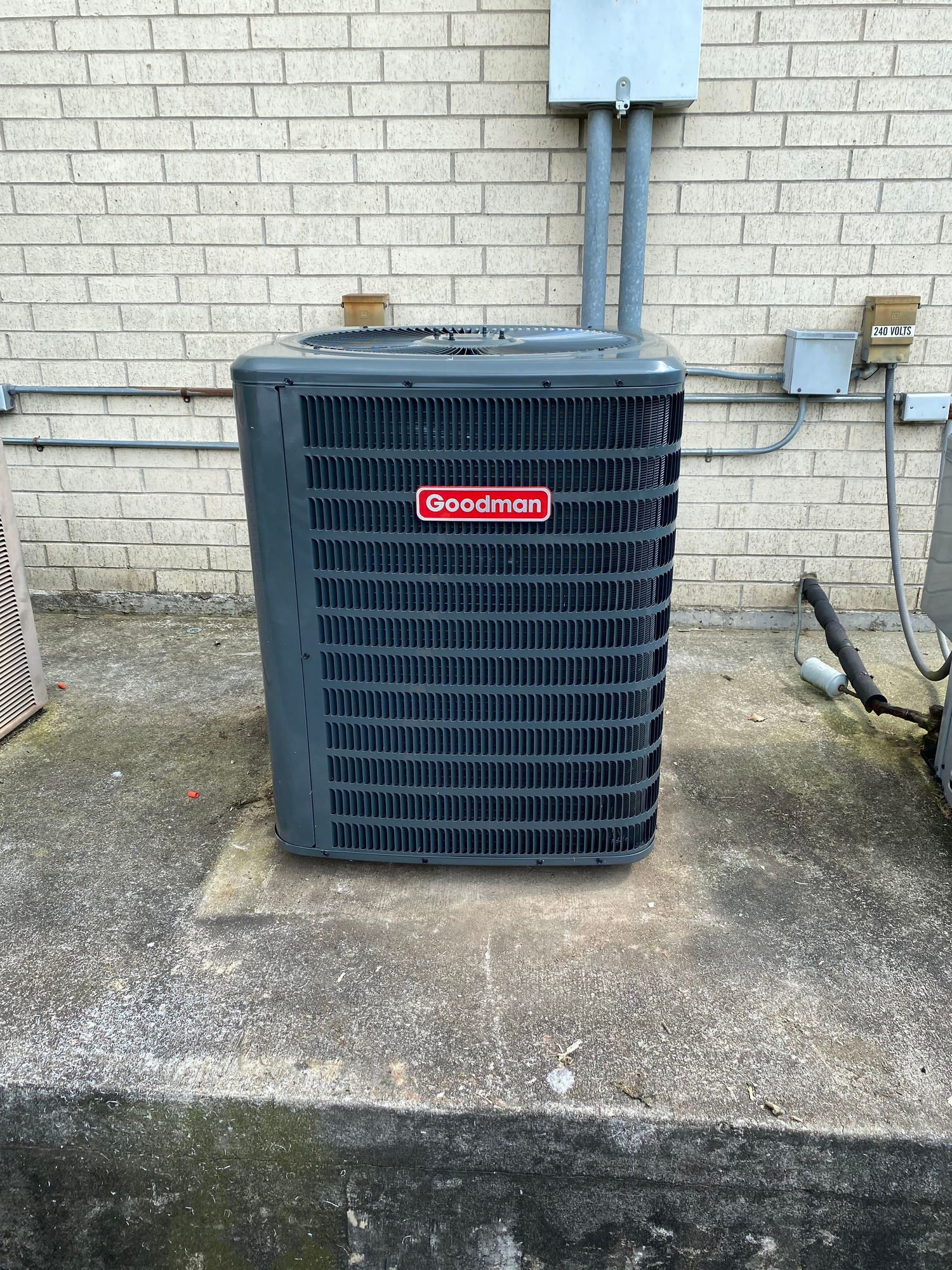 An air conditioner is sitting on the side of a brick building.