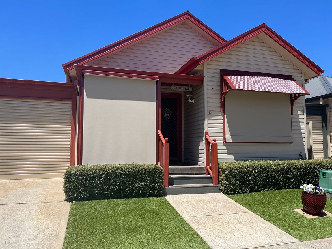 Two dark gray outdoor roller blinds on a building's exterior, partially lowered.