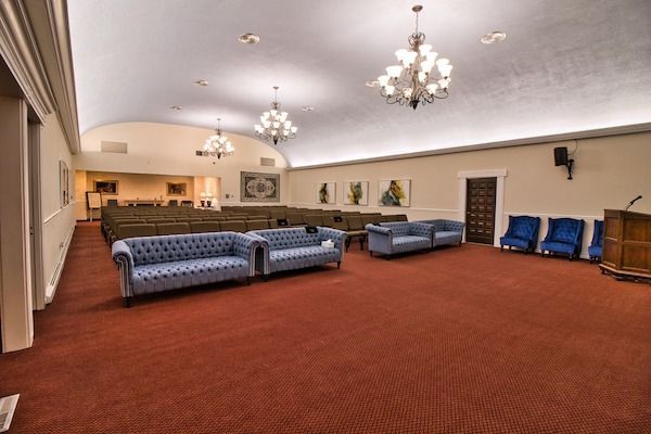 Interior of a room with sofas, chairs, red carpet, and chandeliers.