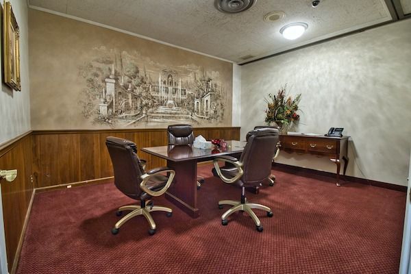 Office room with a large mural, four chairs around a table, and red carpet.