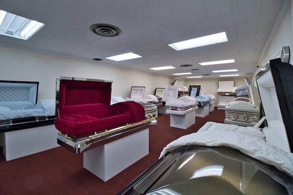 Room with multiple open coffins on display; one with red interior.