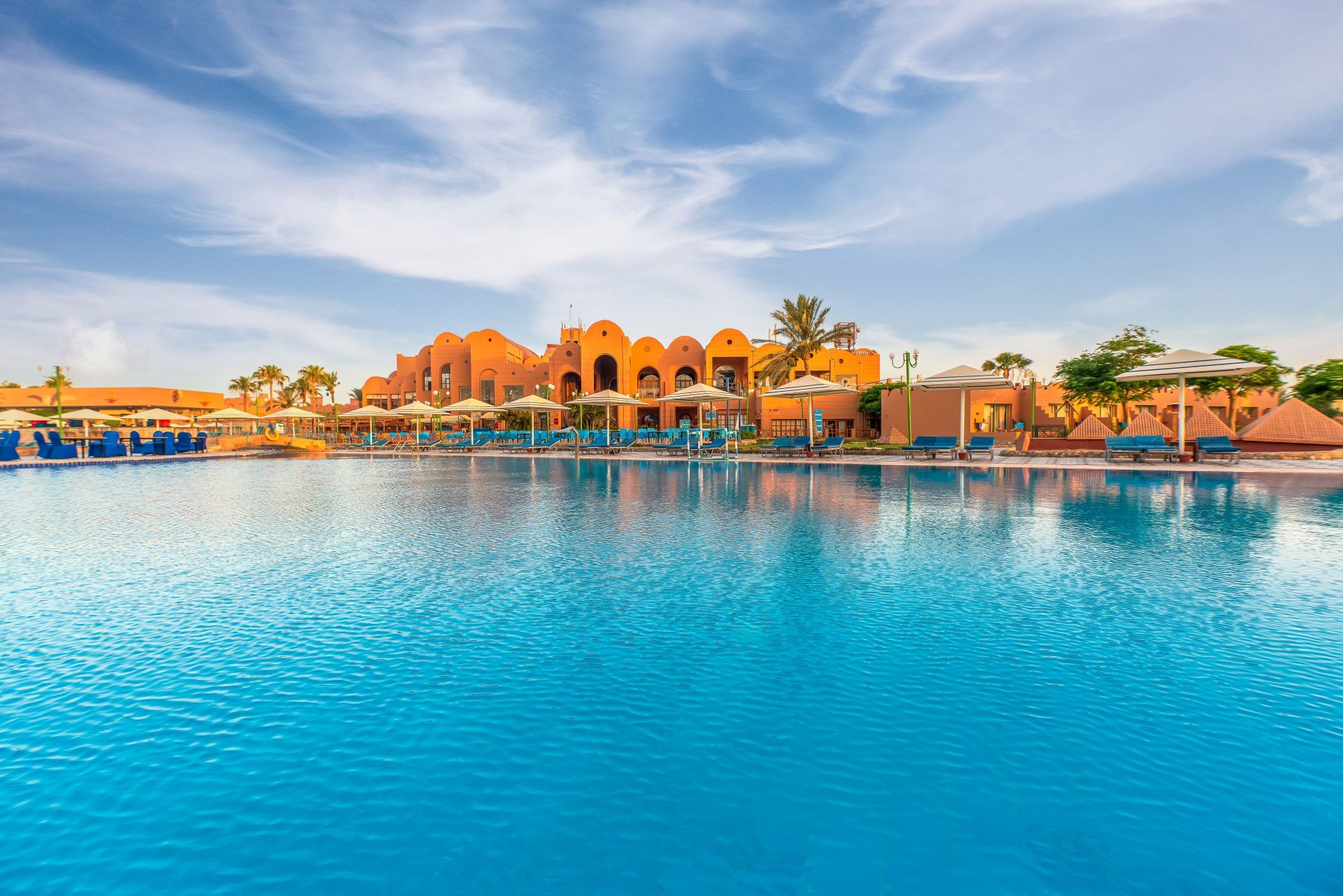 There is a large swimming pool in the middle of a resort.