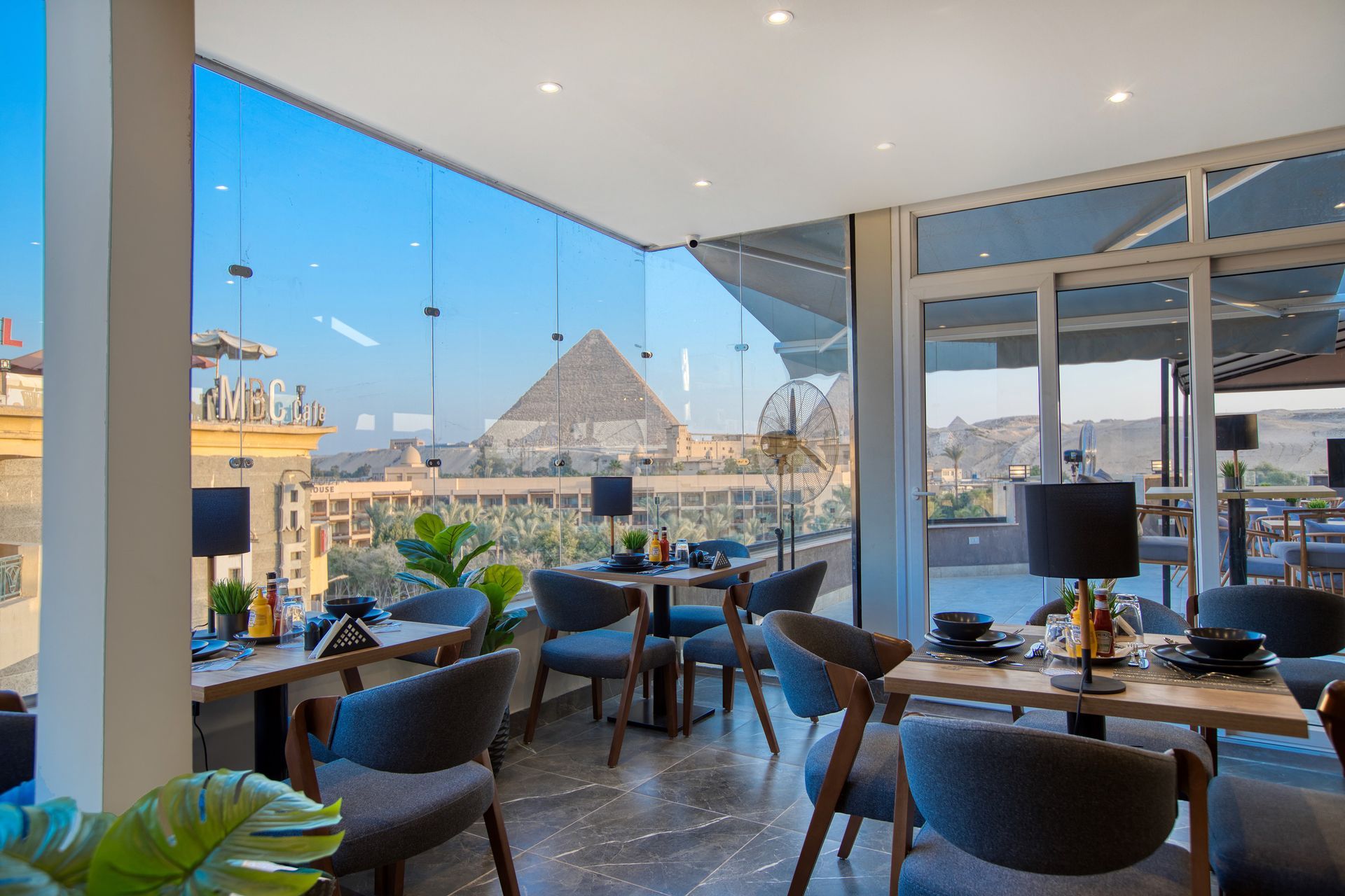 A restaurant with tables and chairs and a view of the pyramids.