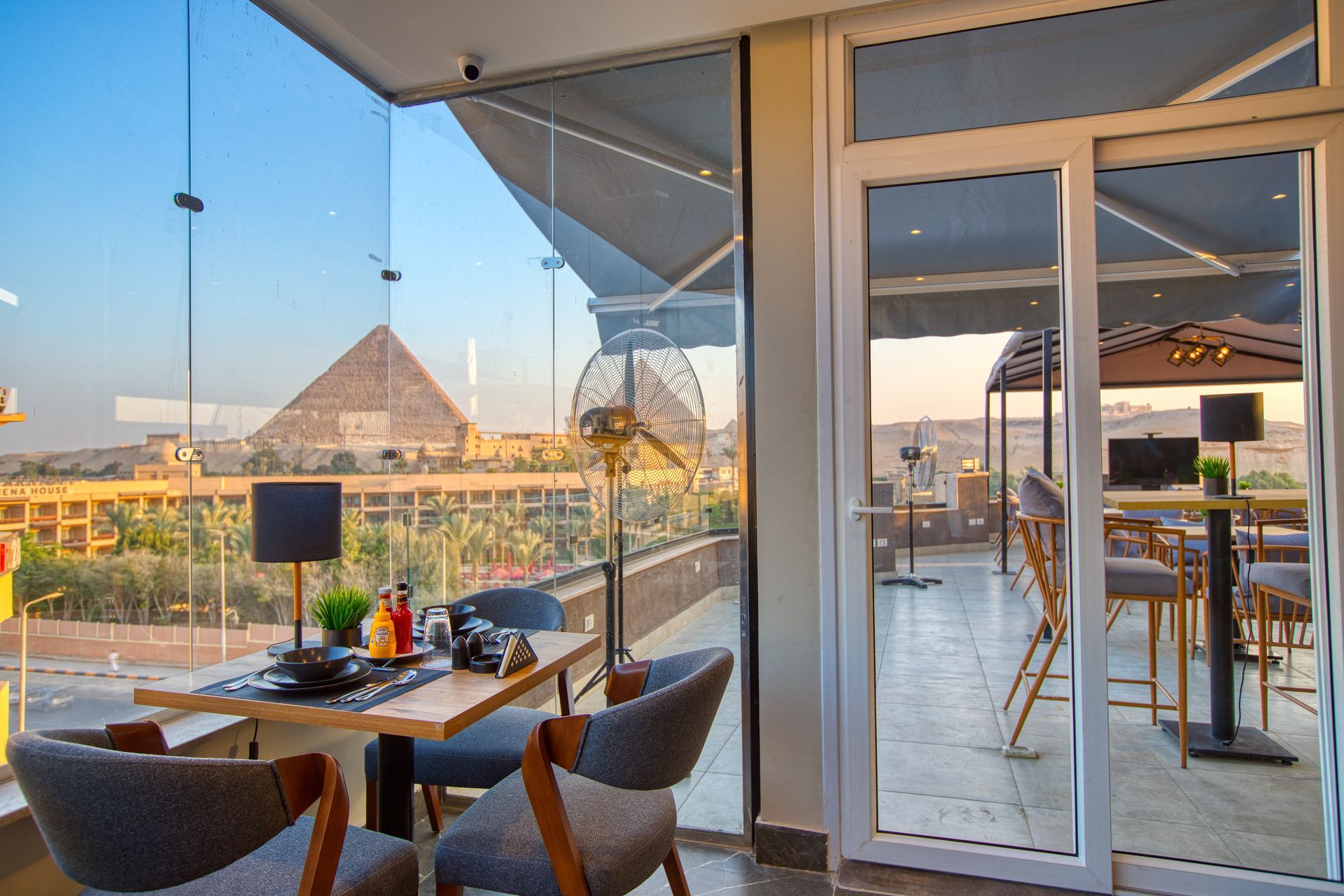 A restaurant with tables and chairs and a view of the pyramids.