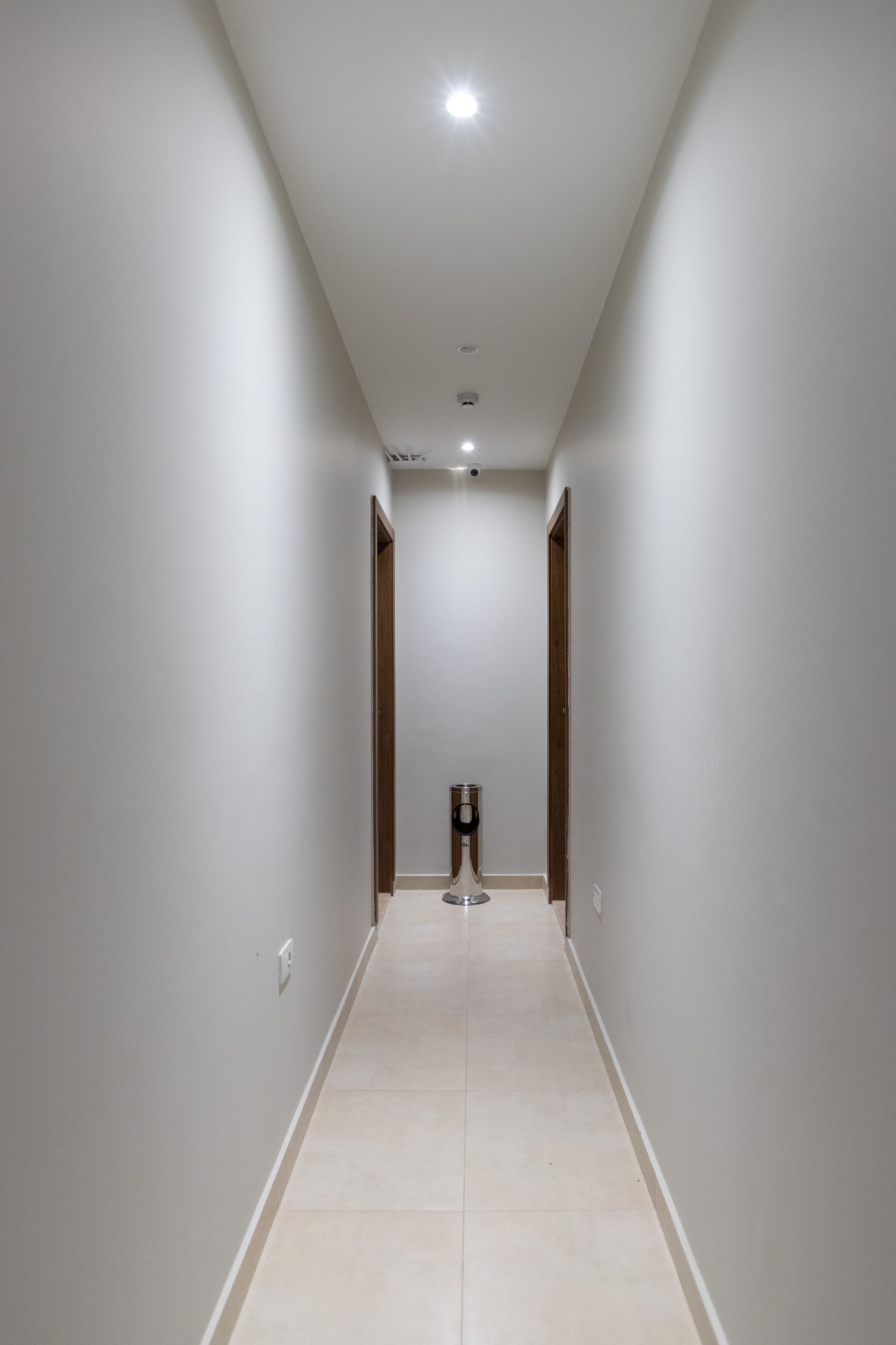 A long hallway with a trash can in the middle of it.