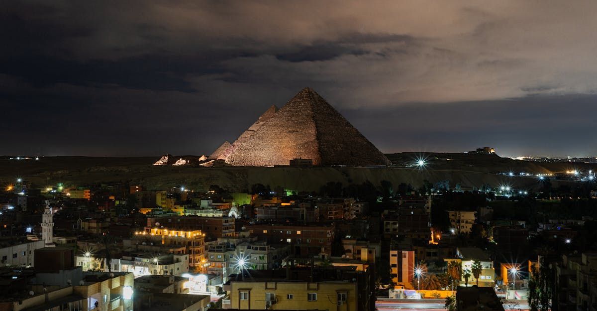 A pyramid is lit up at night in the middle of a city.