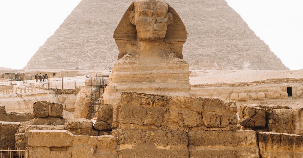 A statue of a sphinx in front of a pyramid.