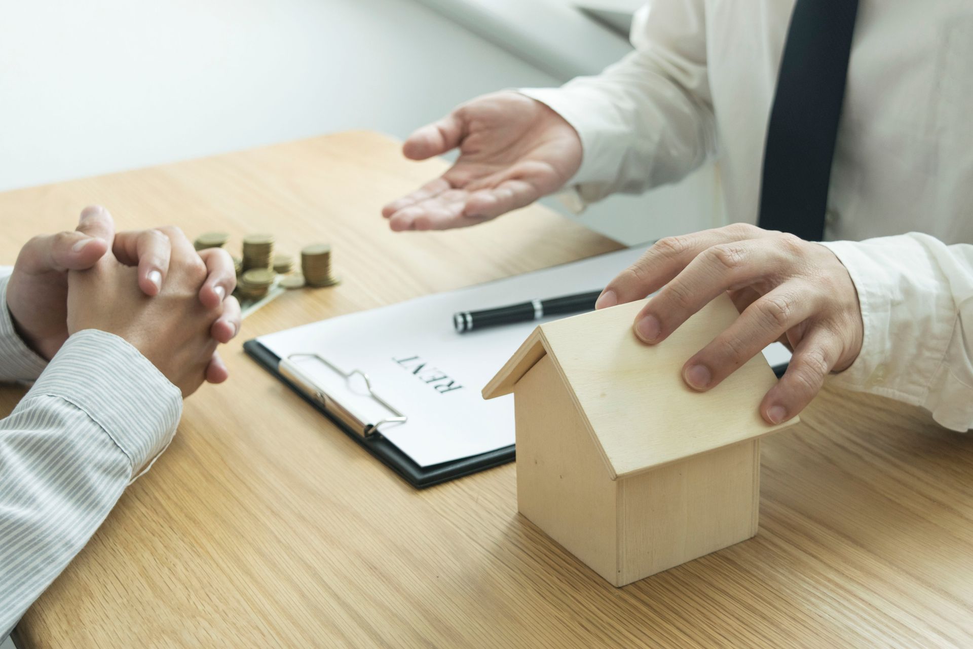 A man is talking to a woman while holding a small wooden house.