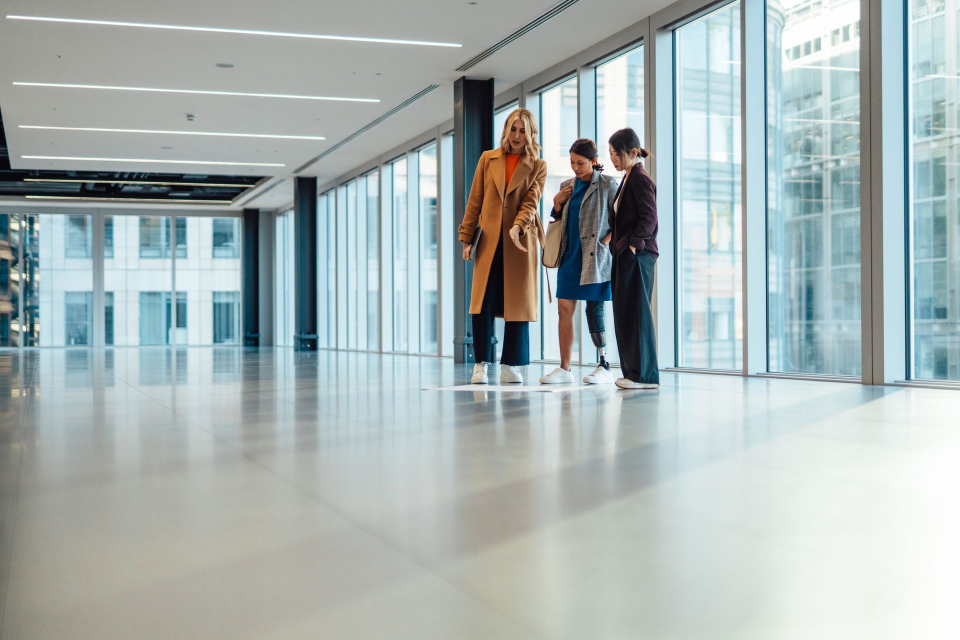 A group of people are standing in an empty building talking to each other.