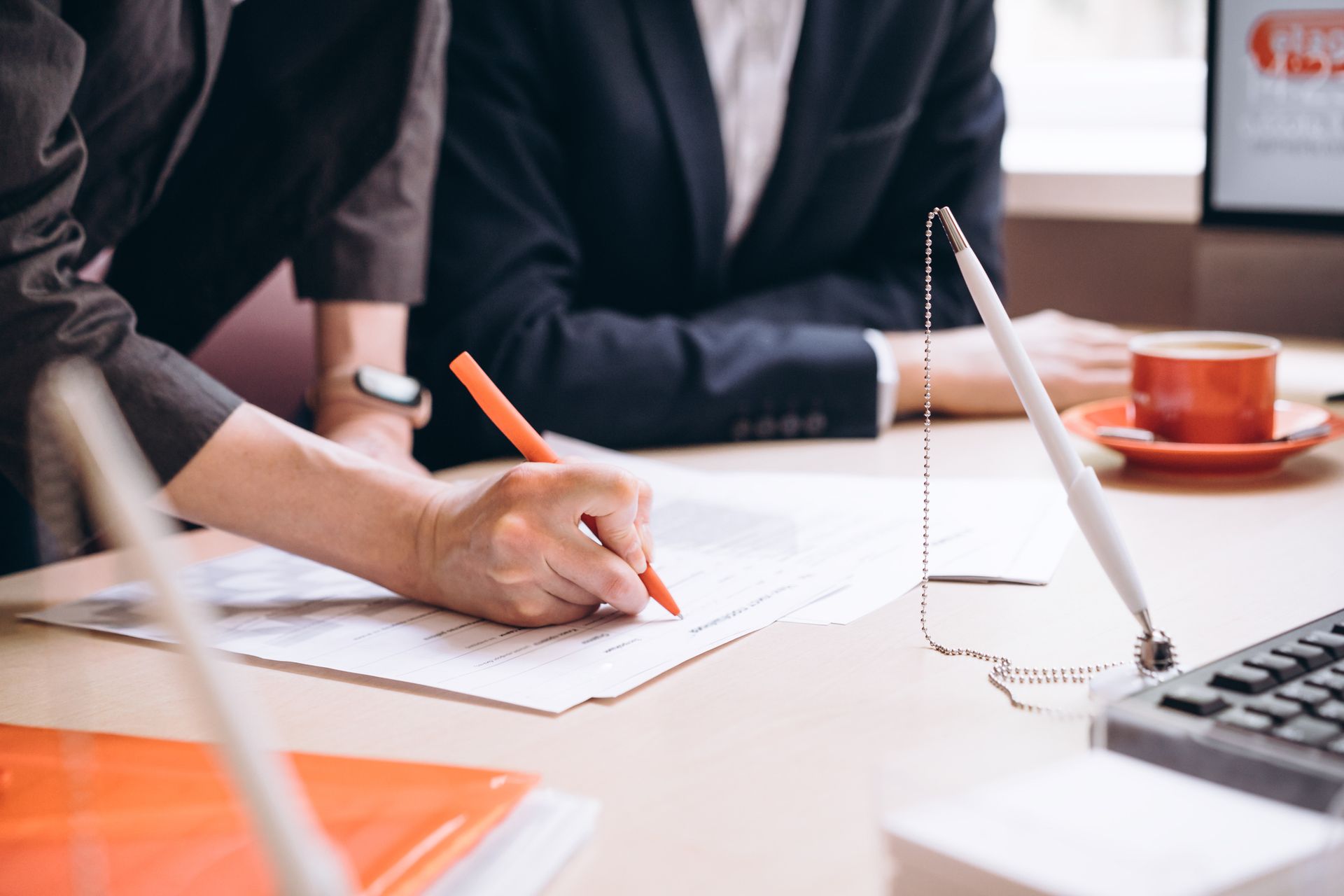 A man and a woman are sitting at a table writing on a piece of paper.