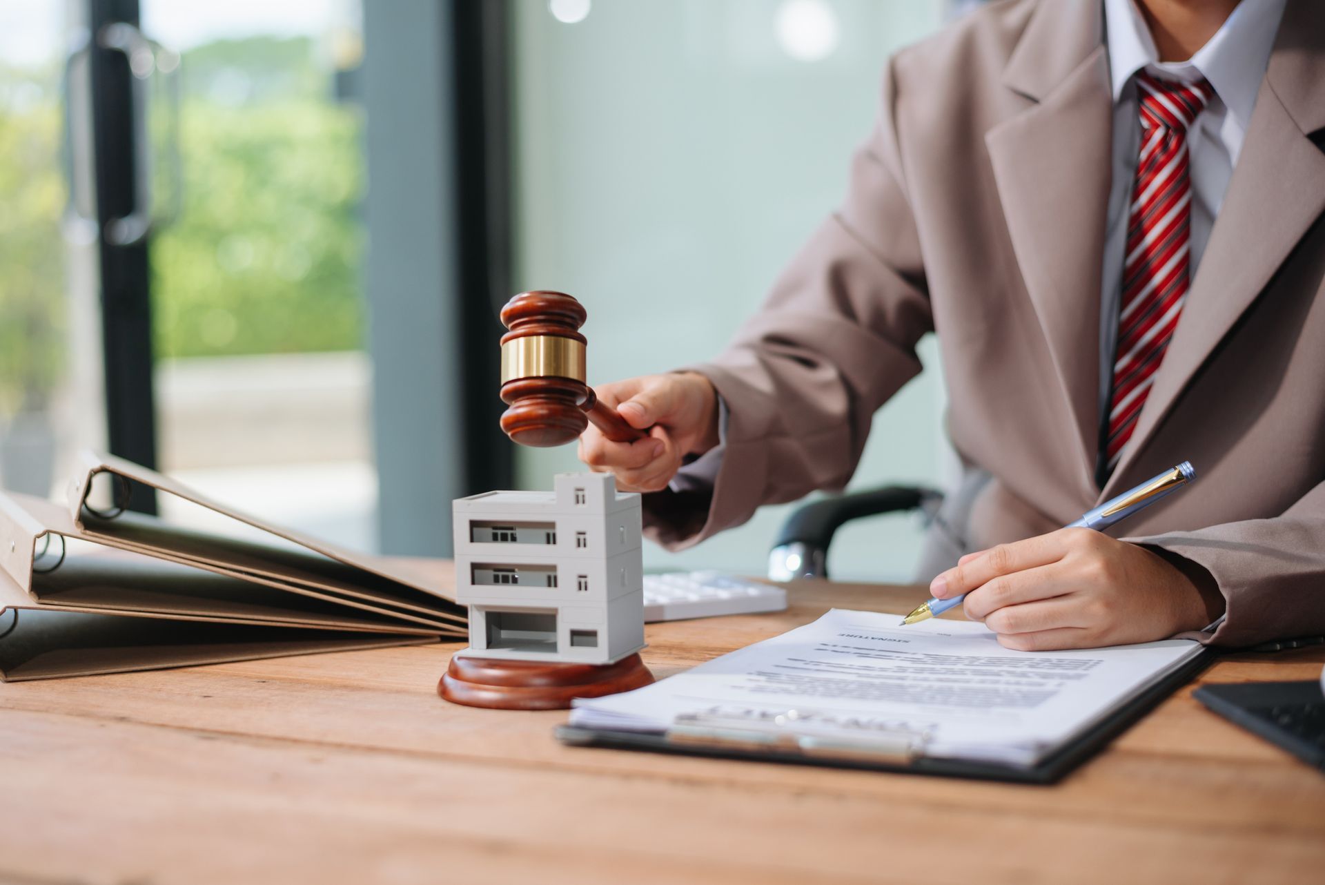 A judge is holding a gavel over a model house.