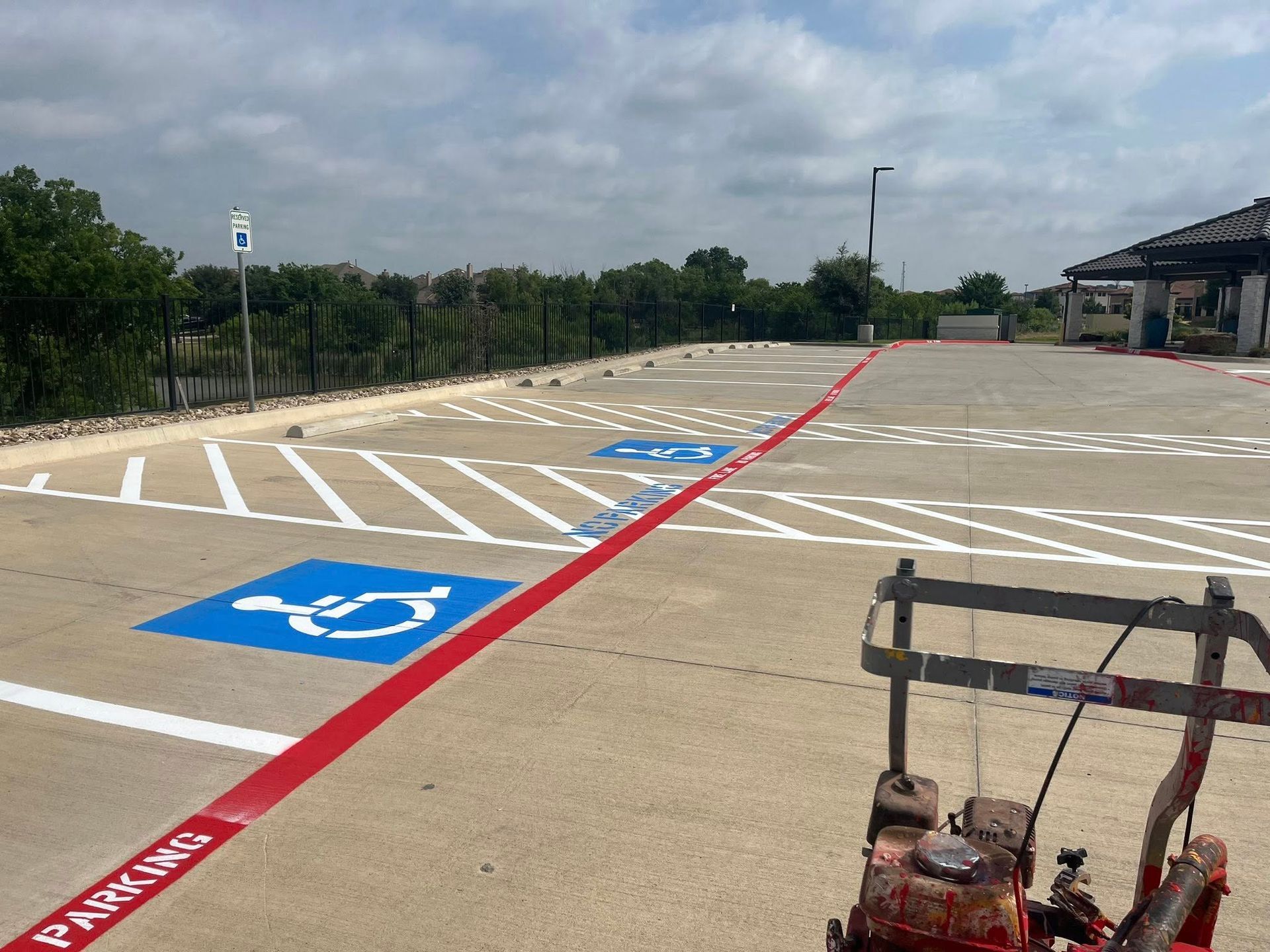 Parking lot with fresh white and red lines, and blue handicap symbols being painted.