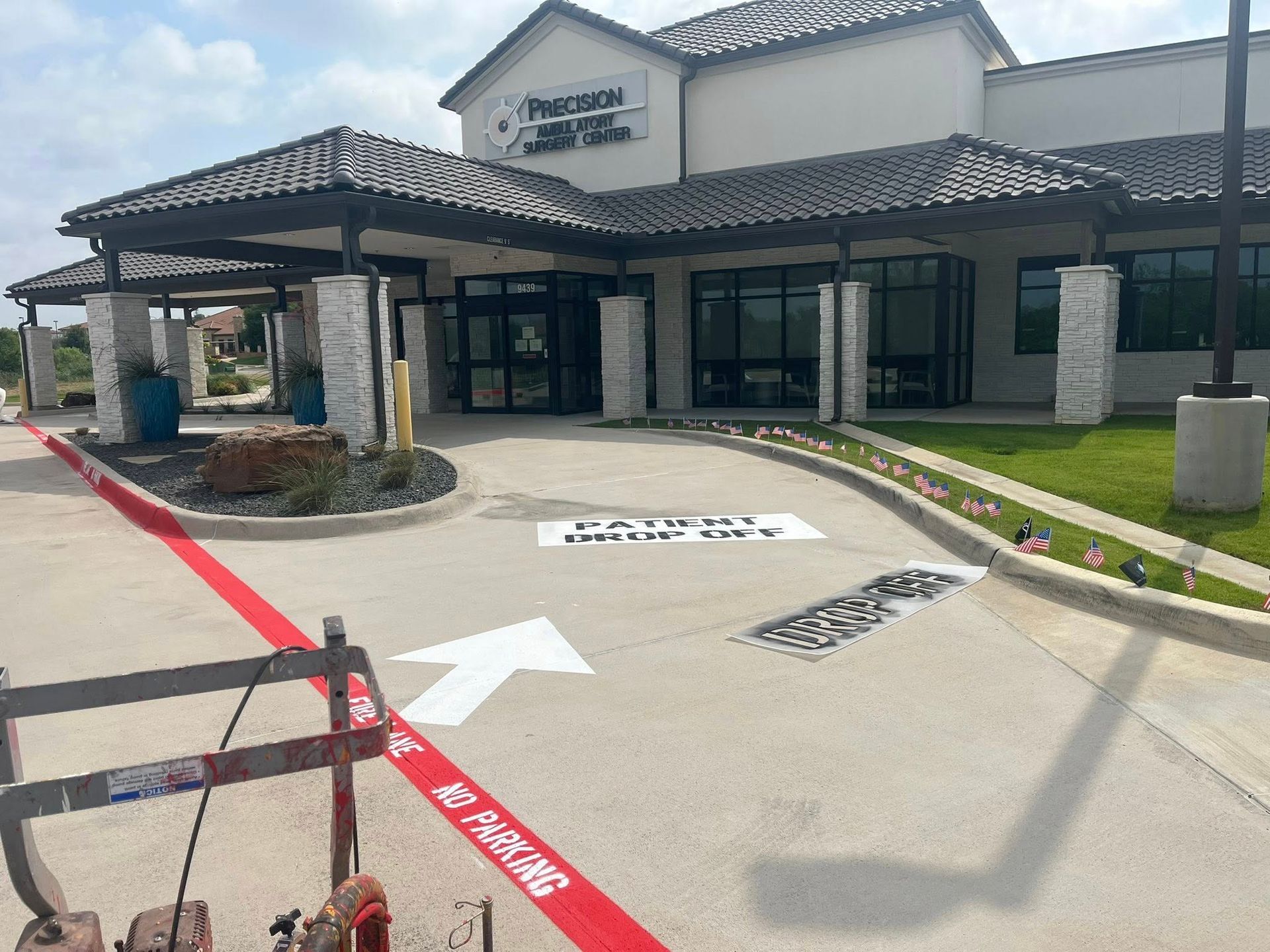 Exterior of a medical building with a red-painted curb; white arrow directs 