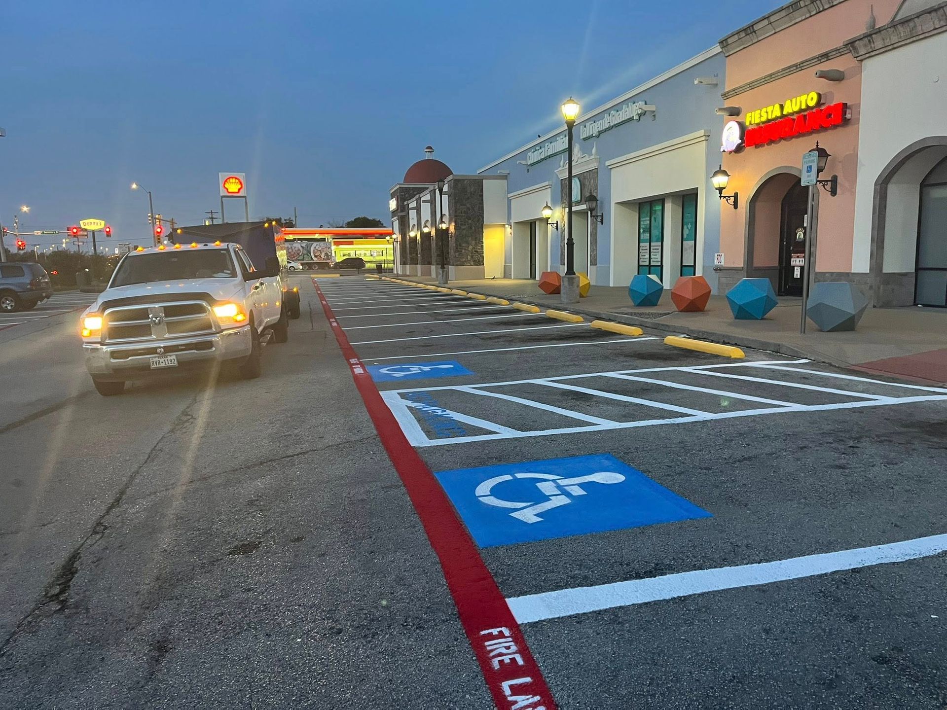 A truck drives past an empty shopping center, with marked accessible parking spaces.