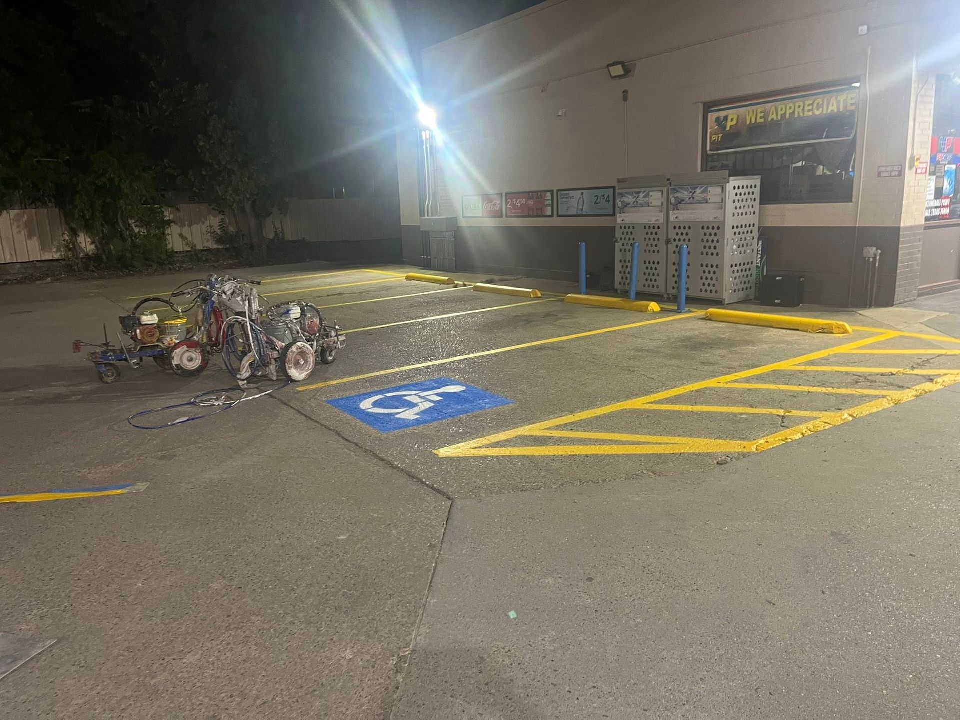 Parking lot with fresh yellow lines and a blue handicap symbol; a machine sits nearby.