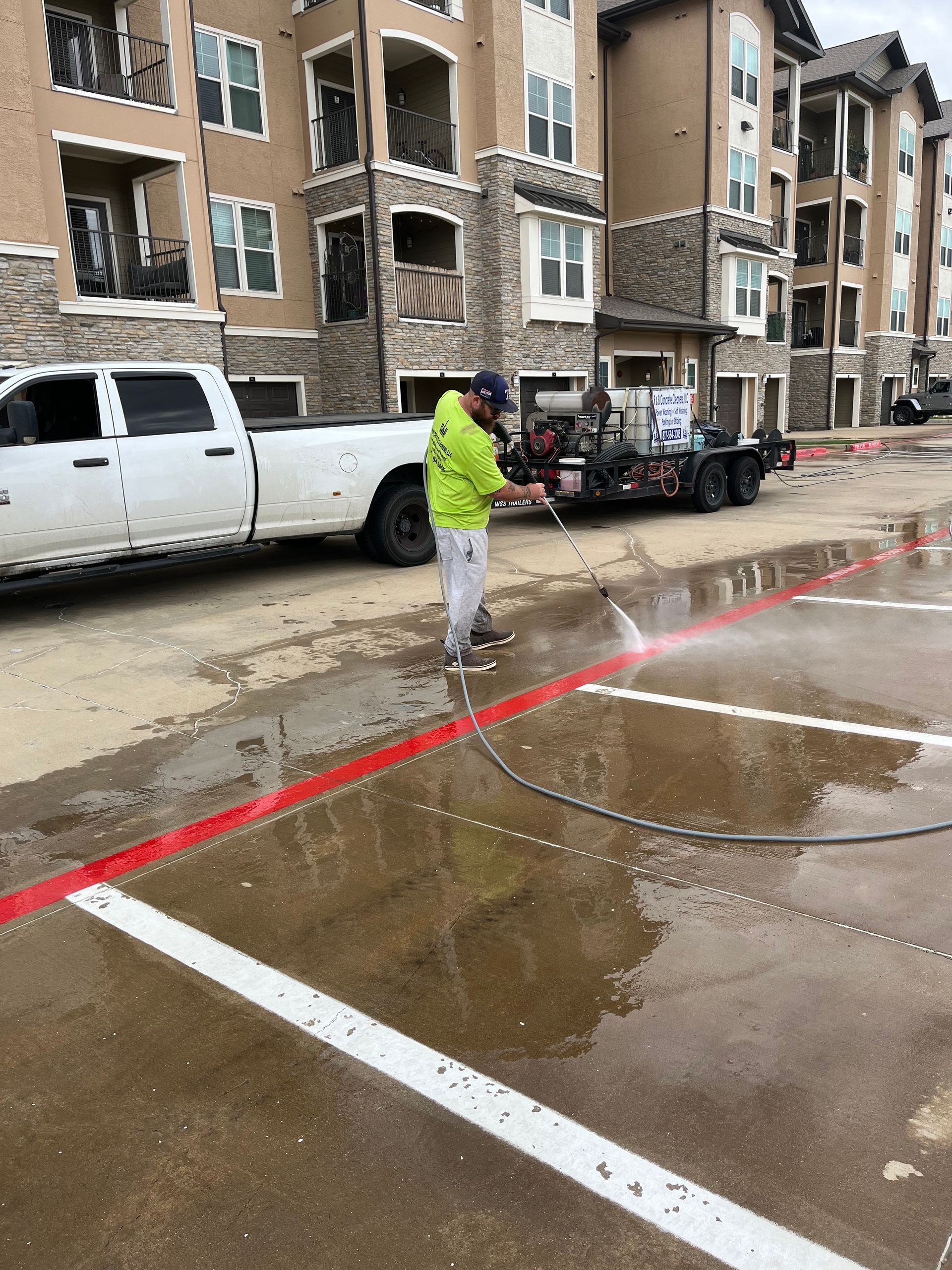 Person pressure washing a brick patio; green bushes in the background.
