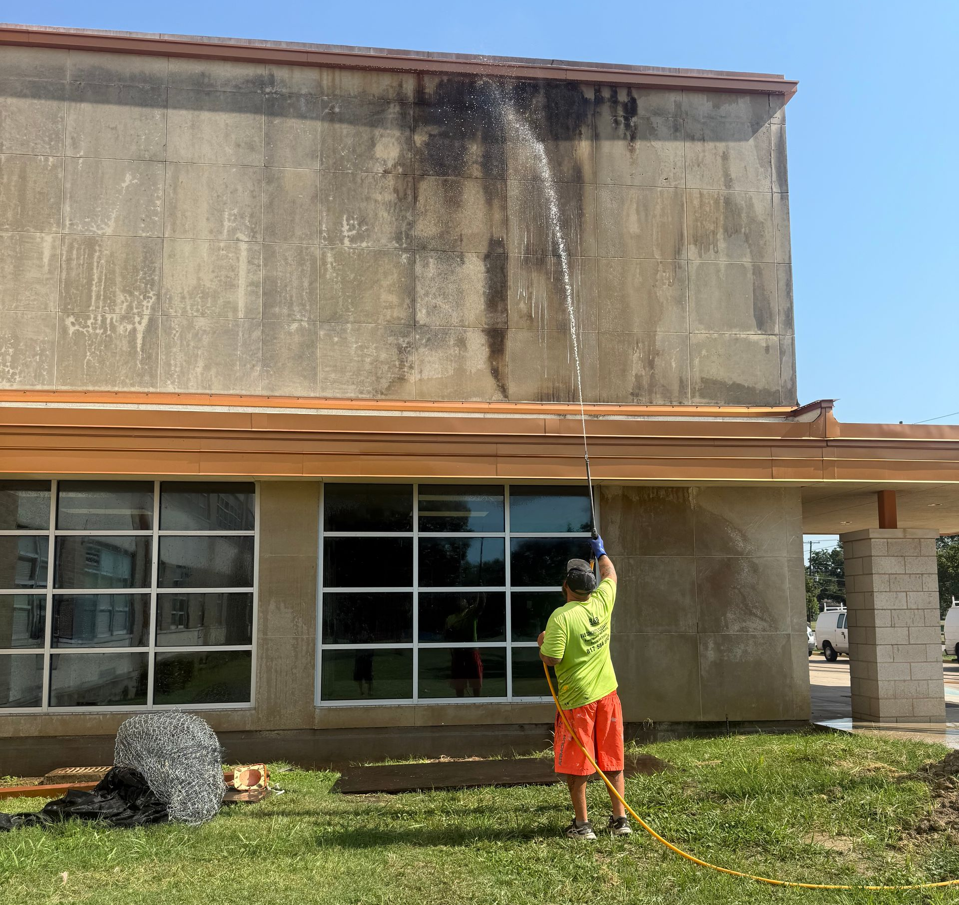 Man power washing a red brick building.