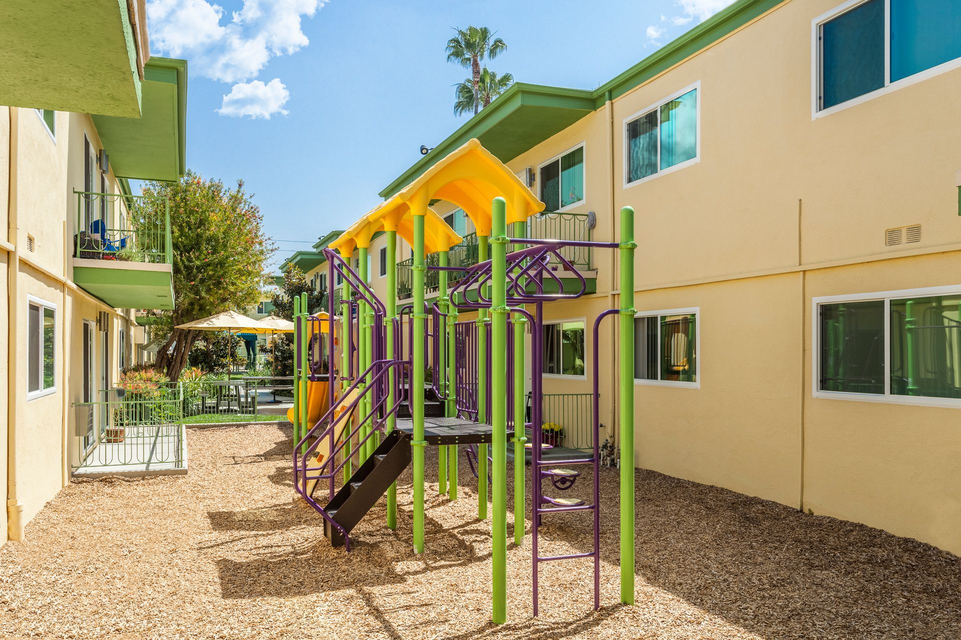 There is a playground in the middle of a courtyard between two buildings.