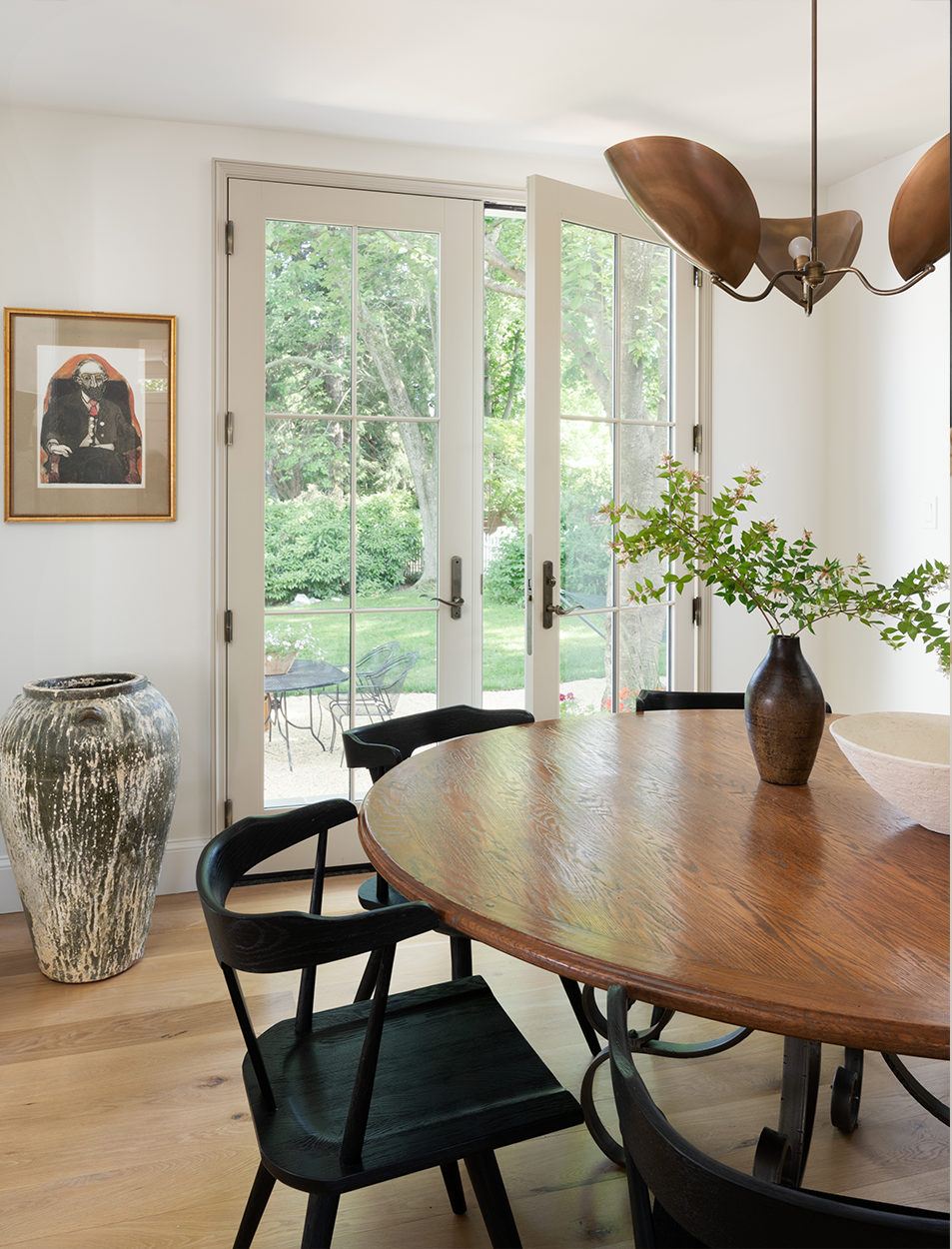 A dining room with a table and chairs and a vase on the table