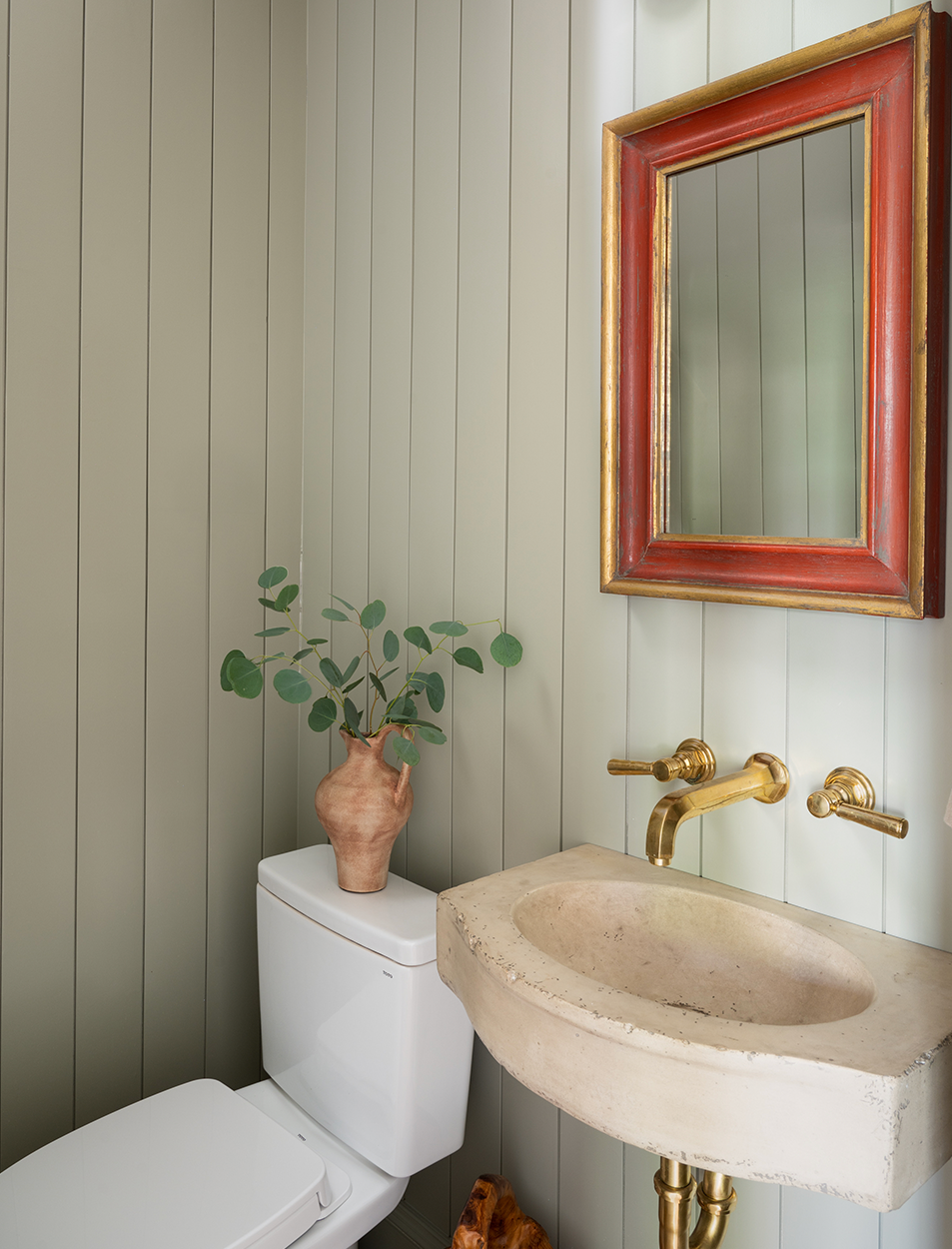 A bathroom with a toilet , sink and mirror.