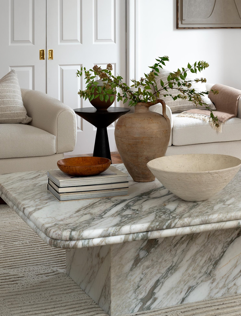 A marble coffee table with vases and bowls on it in a living room.