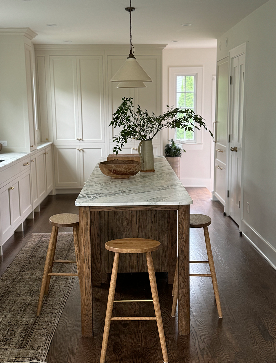 A kitchen with a table and stools and a vase of flowers on it.