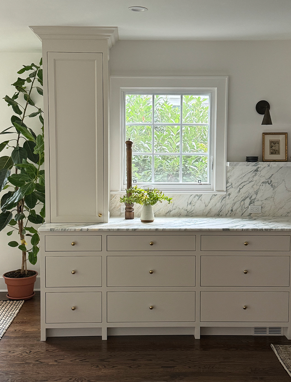 A kitchen with white cabinets , marble counter tops , and a window.