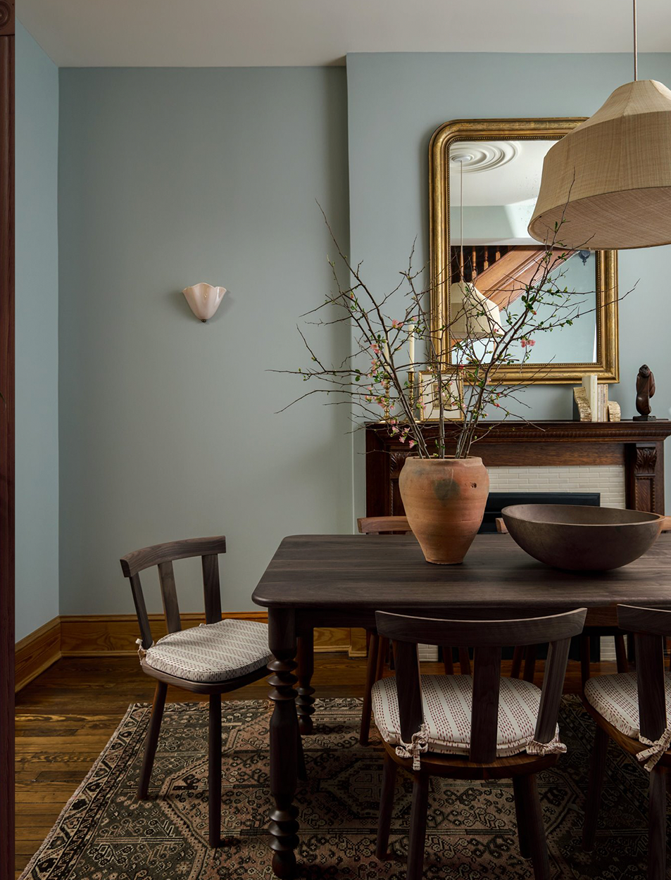 A dining room with a table and chairs and a vase on the table