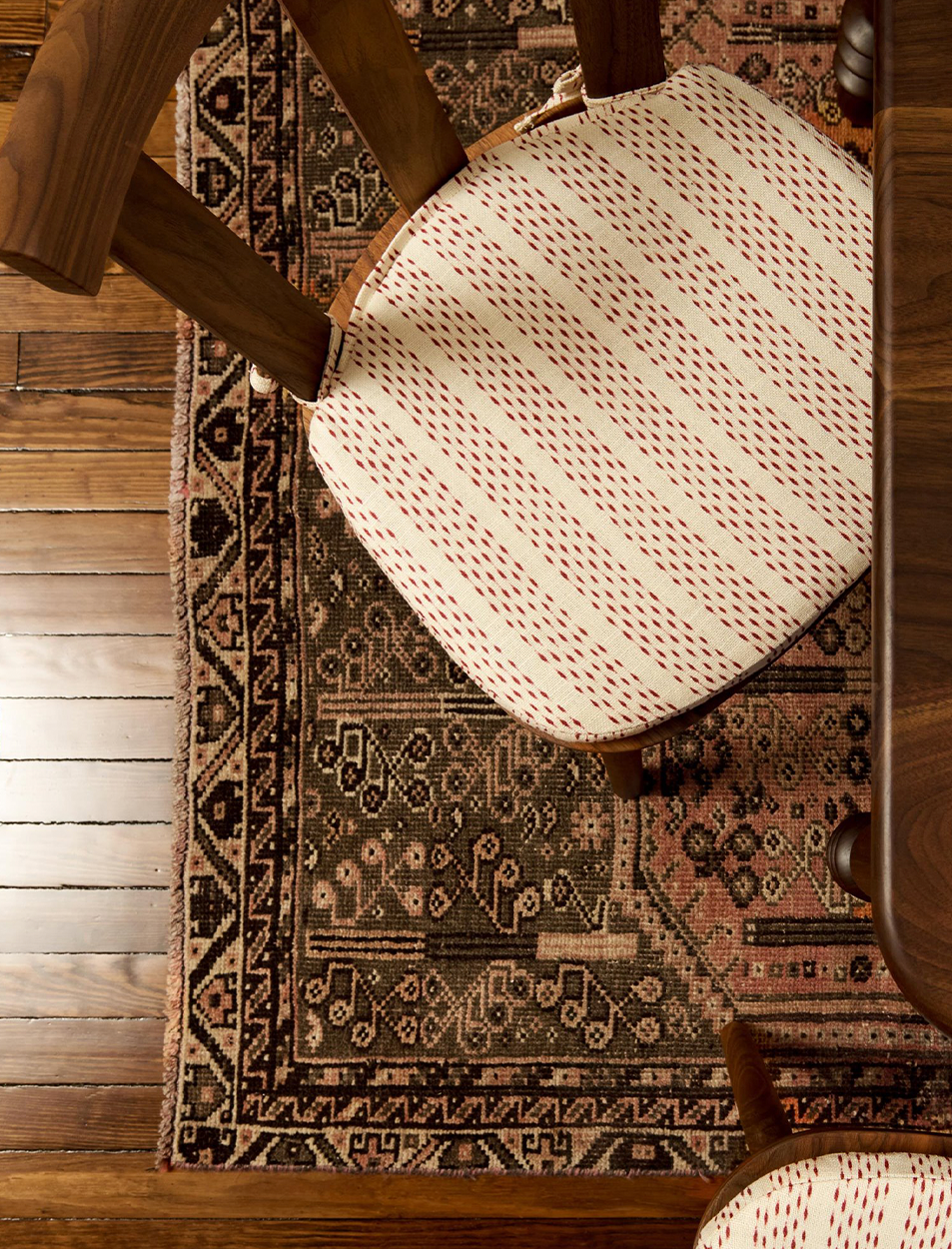 A chair with a cushion on it is sitting on a rug.