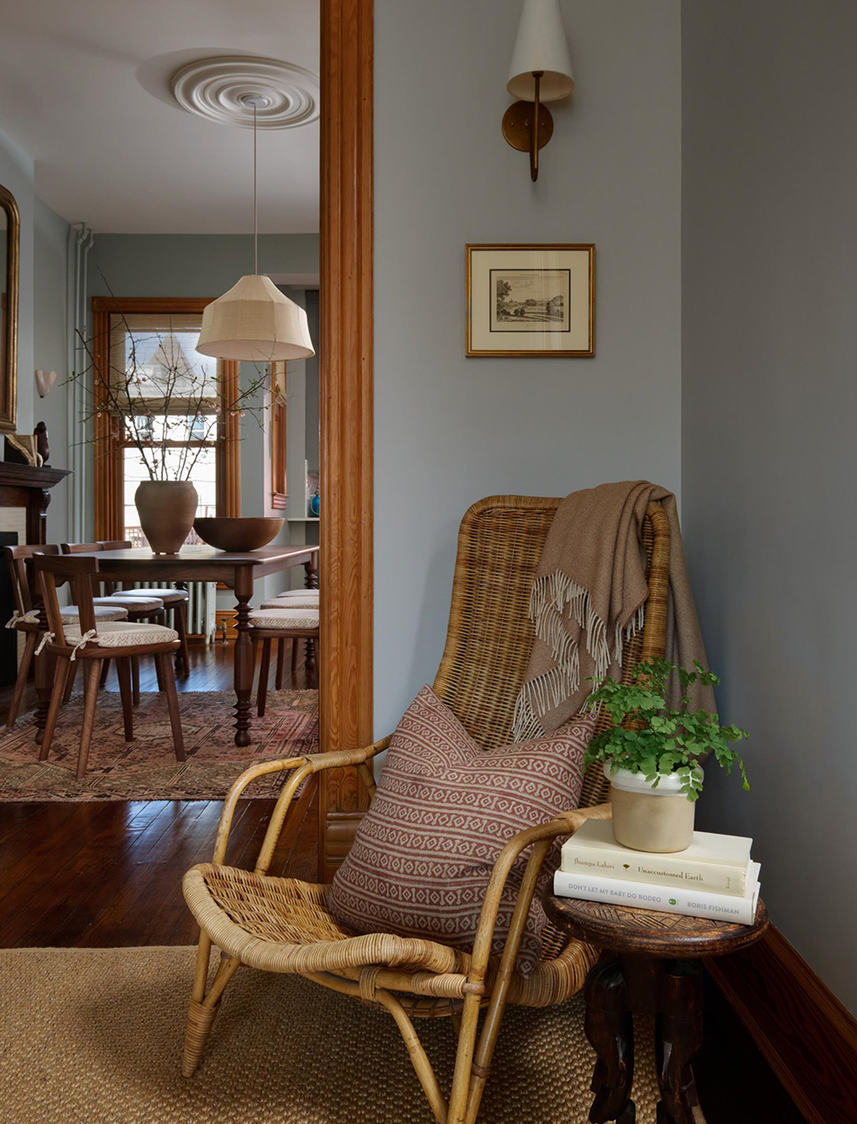 A wicker chair sits in a corner of a room next to a table