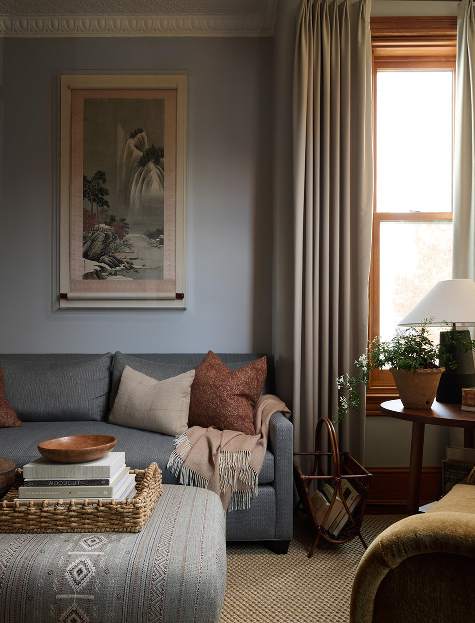 A living room with a couch and a wicker ottoman