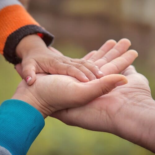 Child's Hand Touching Parents' Hand  — Legal Aide in Merced, CA