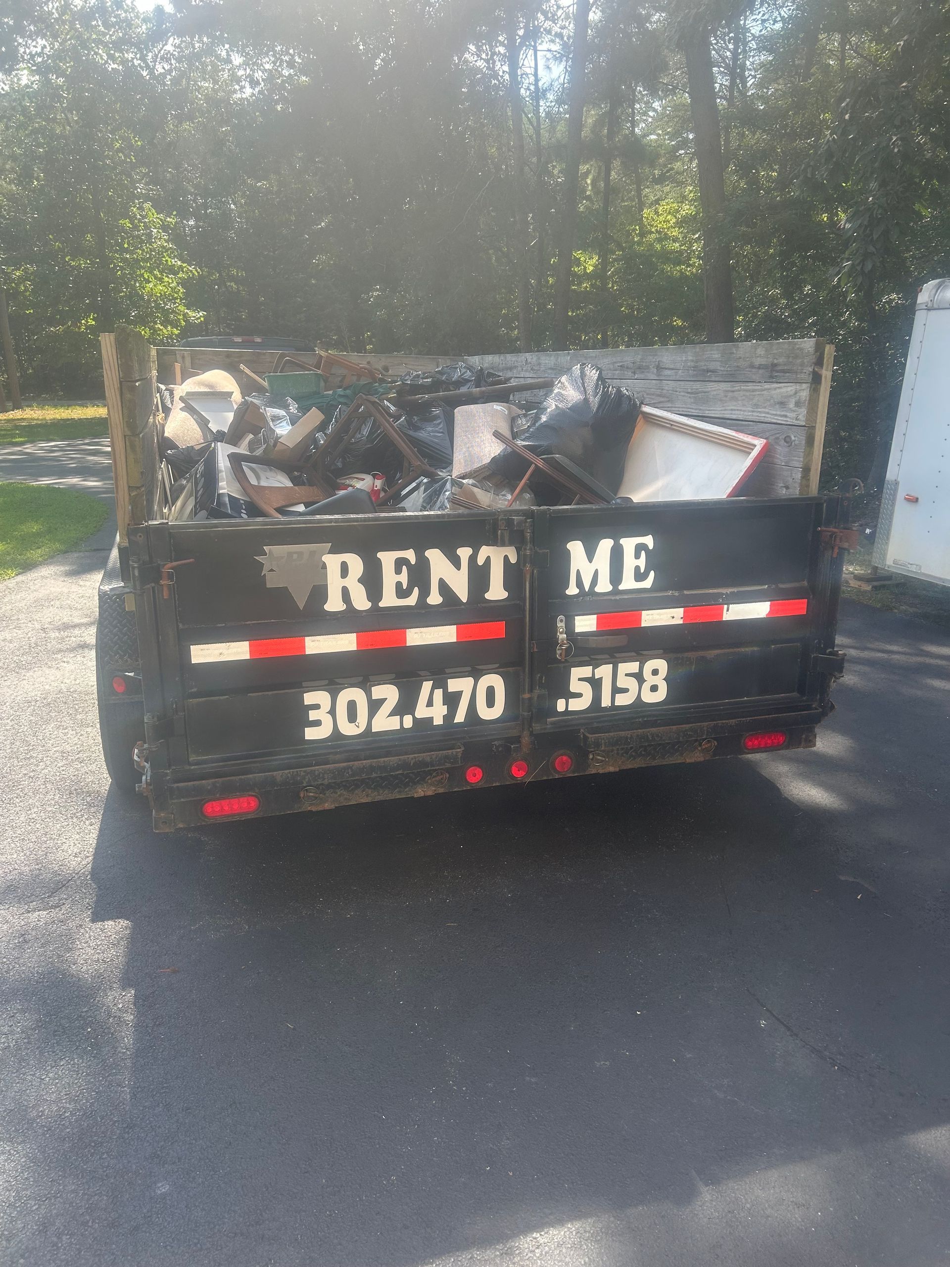 Blue dumpster filled with broken concrete and brick rubble, outdoors.
