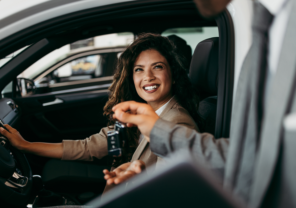 Woman smiling in a car, reaching toward a person in the front seat | 106 St Tire and Wheel