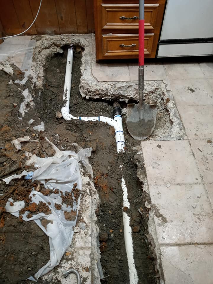 A shovel is sitting in the dirt next to a pipe.