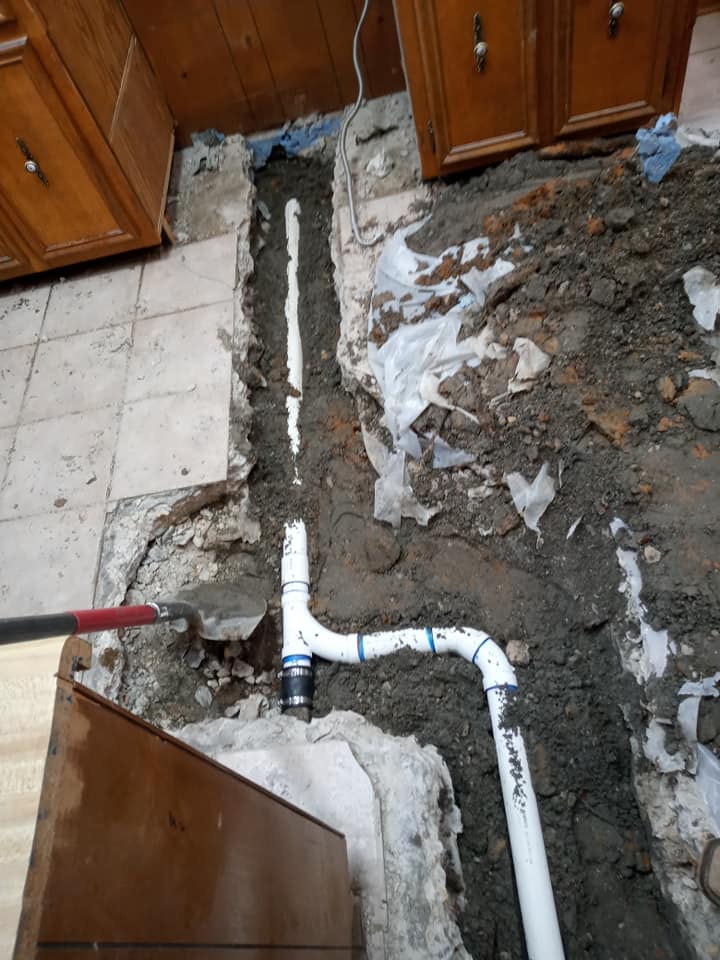 A pipe is being installed in the dirt in a kitchen.