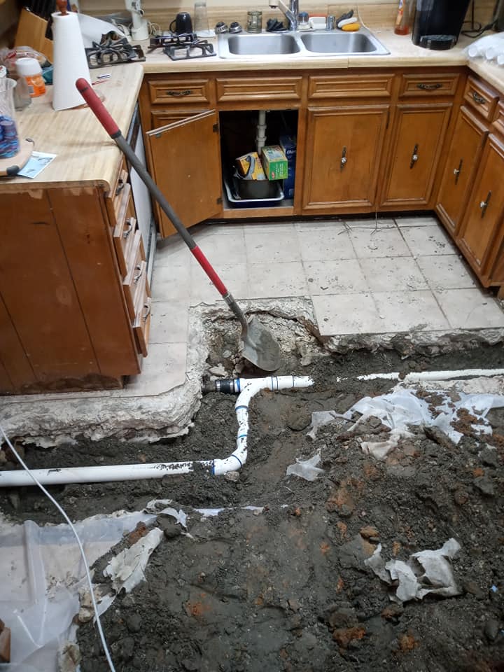 A kitchen with a sink and a shovel in the dirt