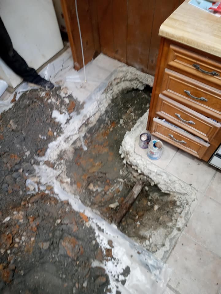 A hole in the floor in a kitchen next to a cabinet