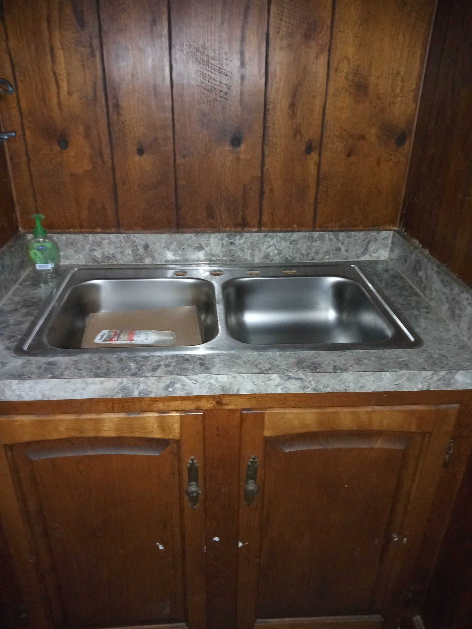 A kitchen sink with a soap dispenser on the counter.