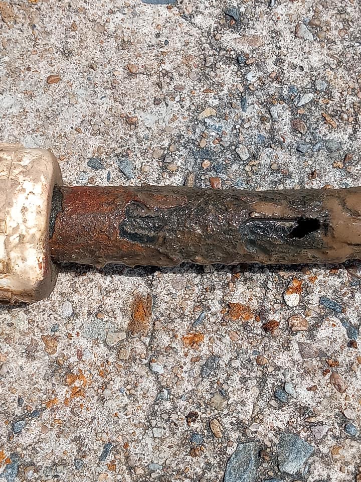 A close up of a rusty piece of metal on the ground.
