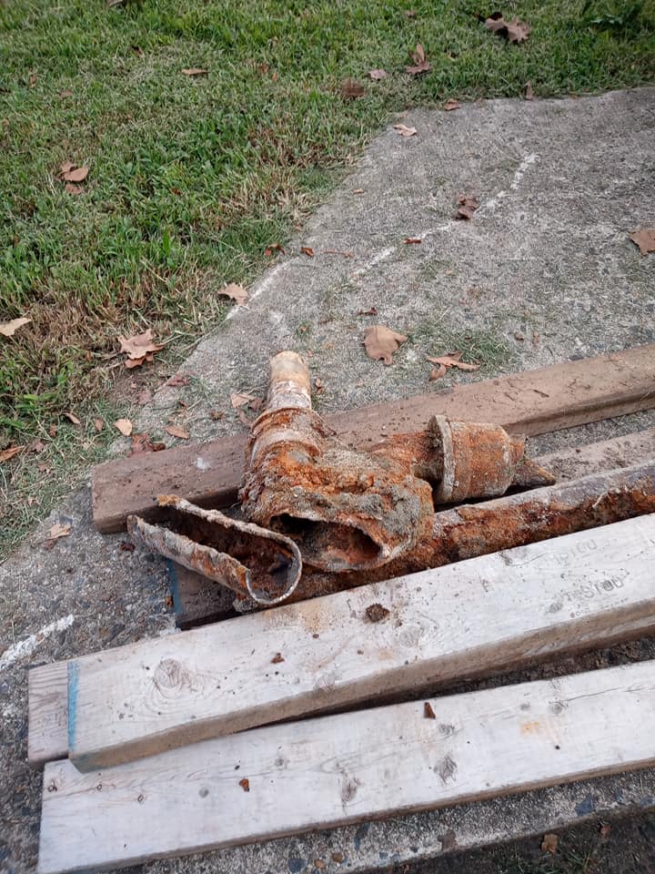A pile of rusty pipes and wood sitting on top of a concrete surface.