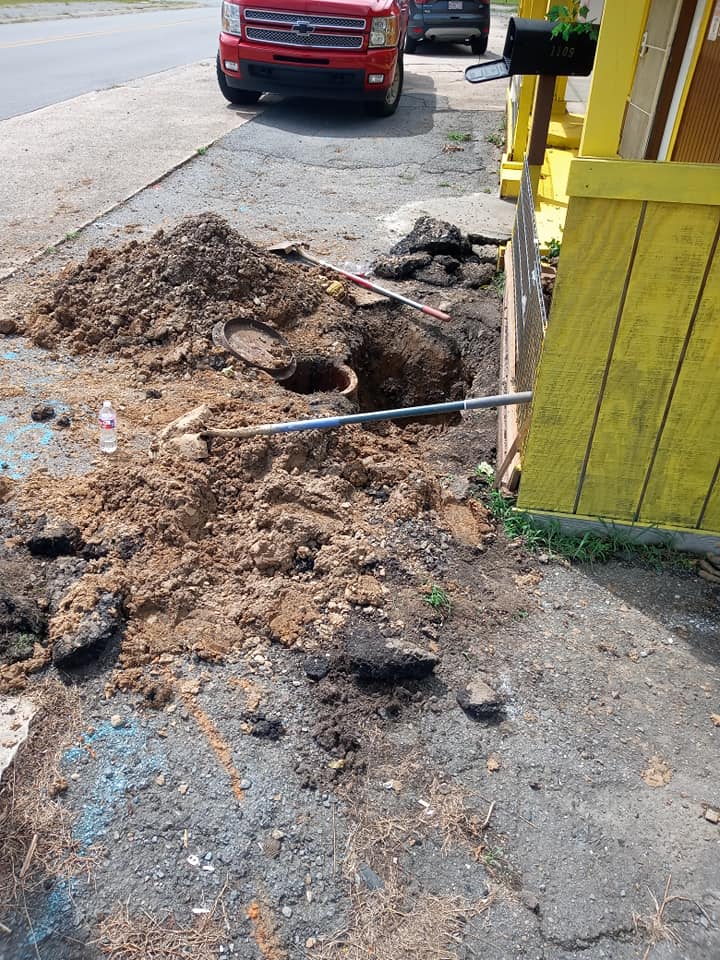 A red truck is parked on the side of the road next to a pile of dirt.