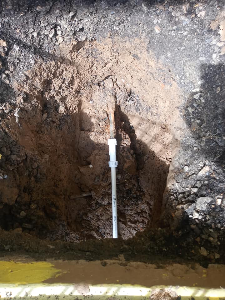 A metal pipe is sticking out of a hole in the ground.