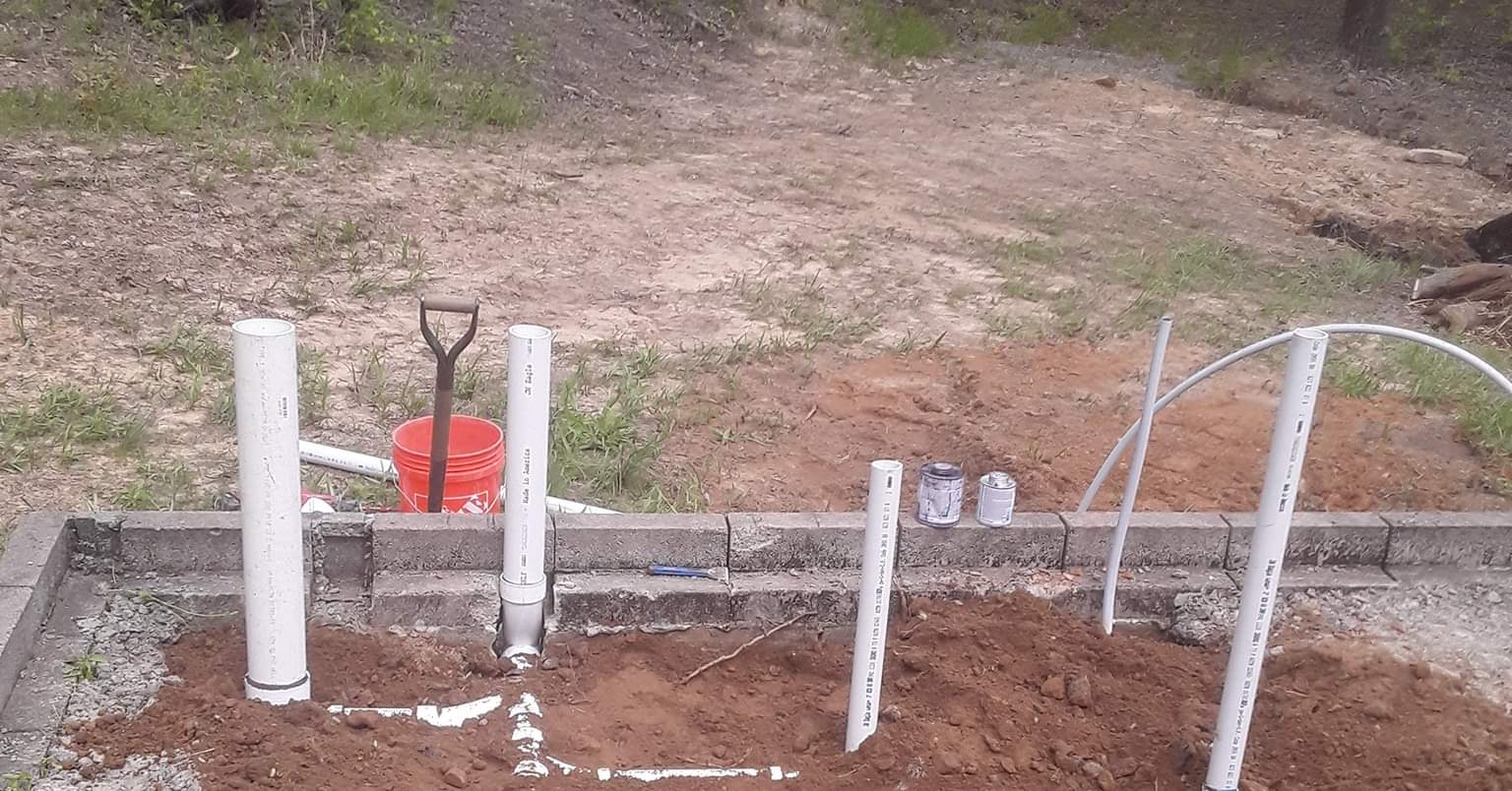 A shovel is sitting on top of a pile of dirt next to a fence.