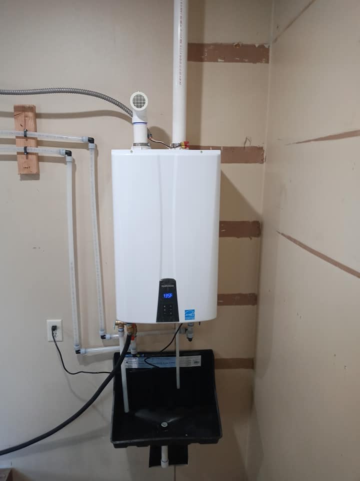 A white water heater is mounted to the wall in a room.