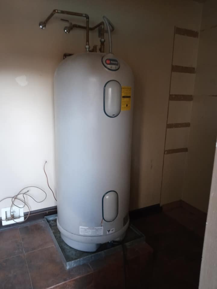 A large gray water heater is sitting on a tiled floor in a room.